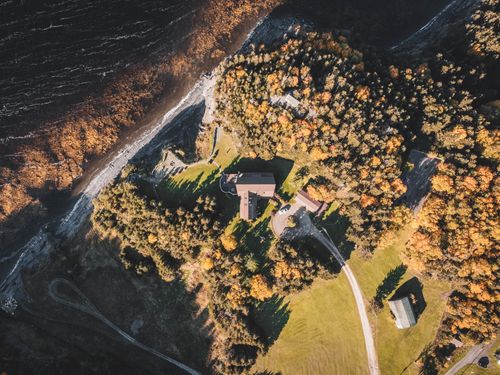 Free A breathtaking aerial shot of a coastline surrounded by autumn-colored woods and houses. Stock Photo