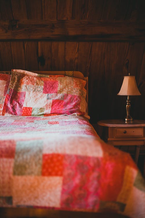 Free A Shot of a Bed and Bedside Cabinet with Lamp on It  Stock Photo
