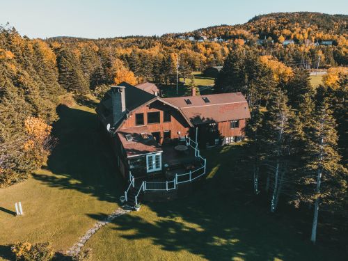 Free Aerial shot of a wooden house nestled in a lush autumn forest, offering a serene retreat. Stock Photo