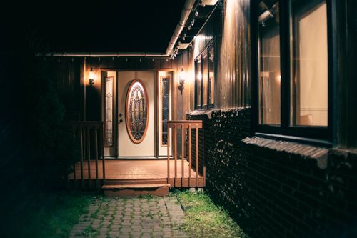 Free A warmly lit house entrance with decorative glass doors and glowing lantern lights at night. Stock Photo
