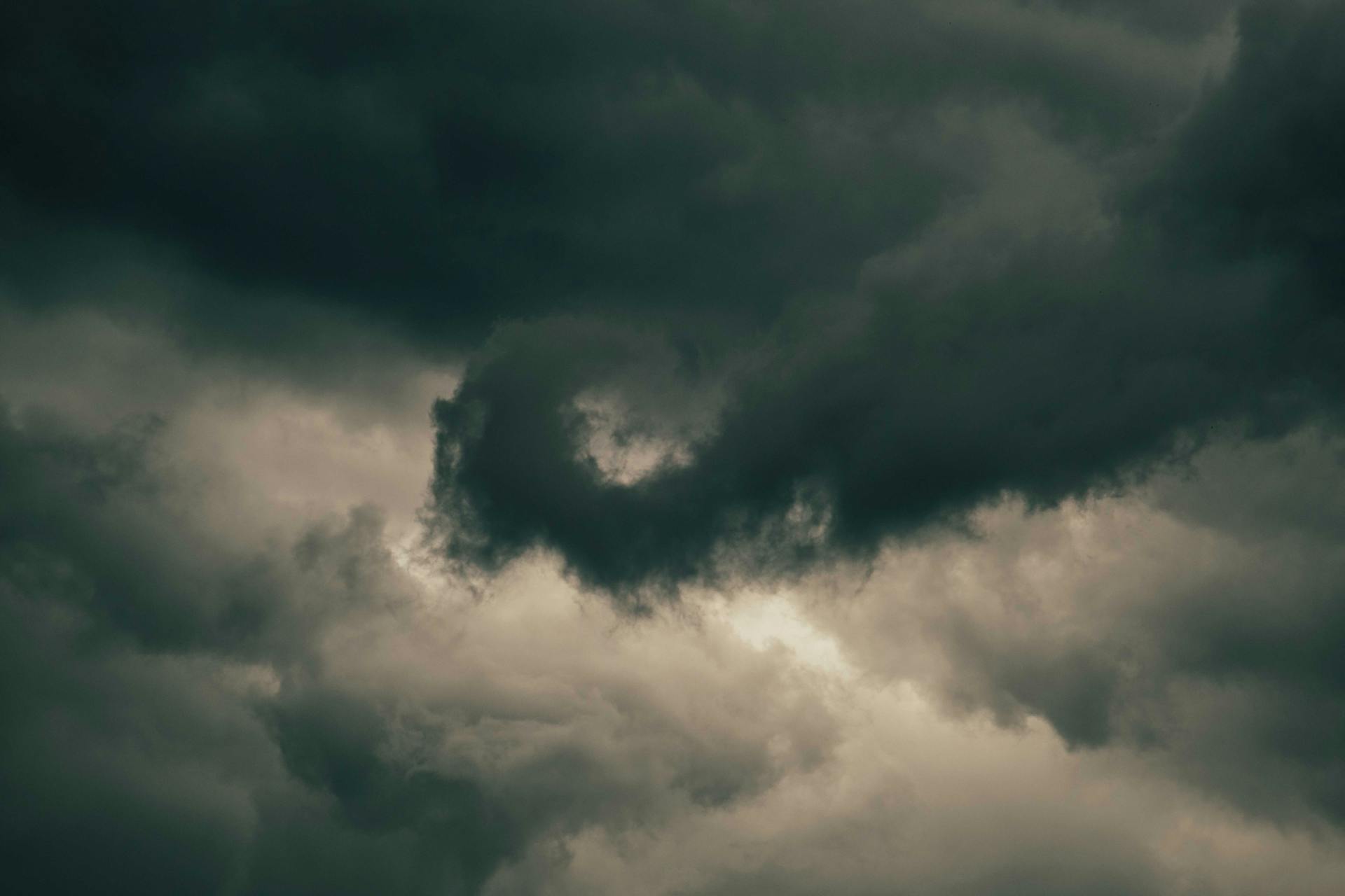 A swirling mass of dark clouds creates a dramatic and moody overcast sky.