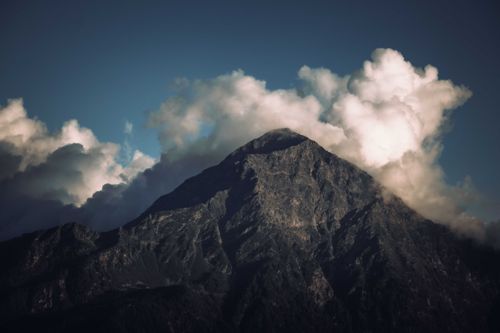 Free A striking rocky mountain peak shrouded by dramatic clouds on a clear day, perfect for nature photography. Stock Photo