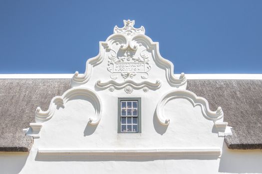 Charming Cape Dutch facade with ornate gable. Ideal for architectural enthusiasts and travel imagery.