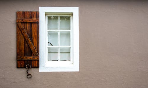 Window with a Wooden Shutter in a Beige Wall