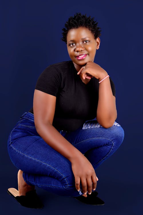 Woman in a Black Shirt Crouching while Her Hand is on Her Chin