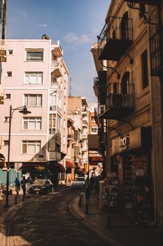 A bustling urban street scene with cafes, shops, and classic architecture under a bright sky.