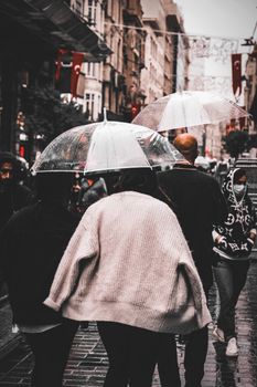 People walking under umbrellas on a rainy day in Istanbul's bustling Istiklal Street.