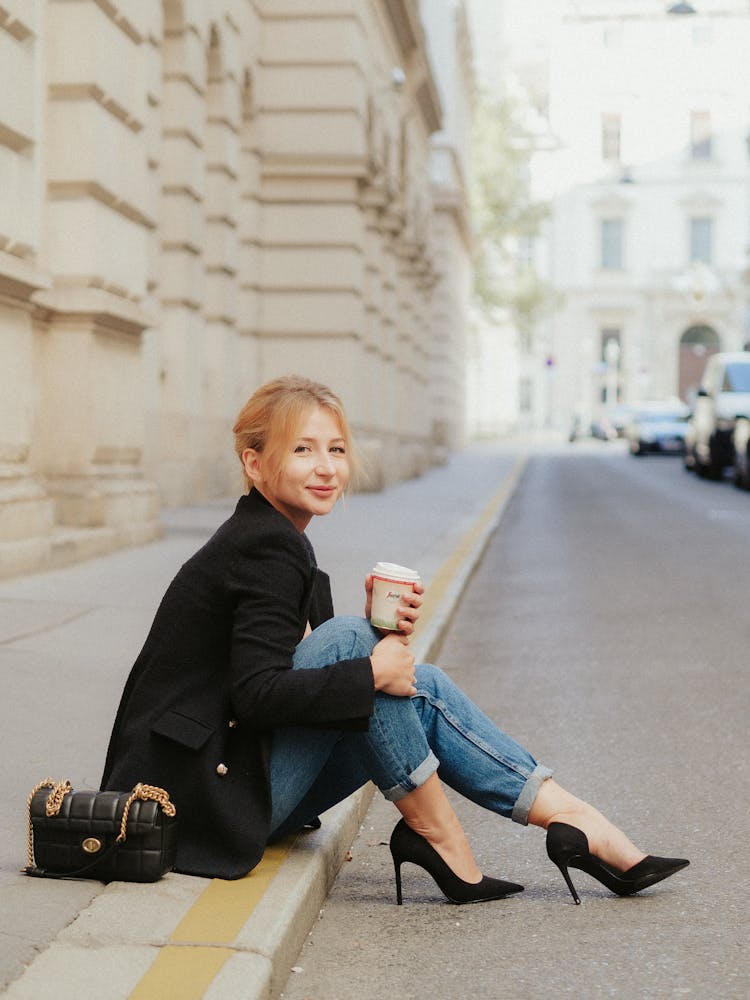 Portrait Of Woman In Jeans And Jacket Sitting On Street