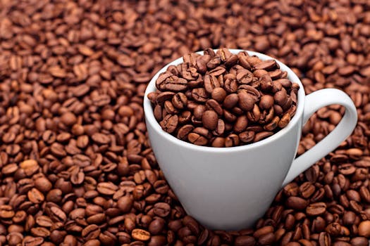 A white ceramic mug full of coffee beans surrounded by a background of coffee beans, showcasing a rich coffee theme.
