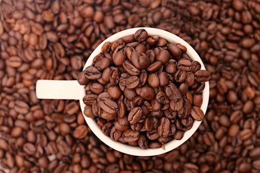 High-angle shot of roasted coffee beans overflowing from a white cup, creating a rich texture.