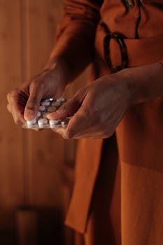 Close-up image of a person holding pills indoors, depicting healthcare concept.