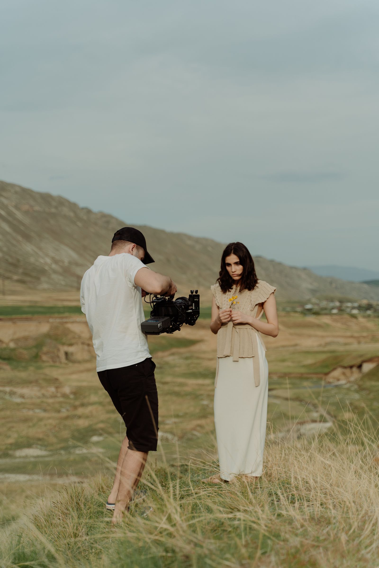 Director and camera operator shooting an actress in a field