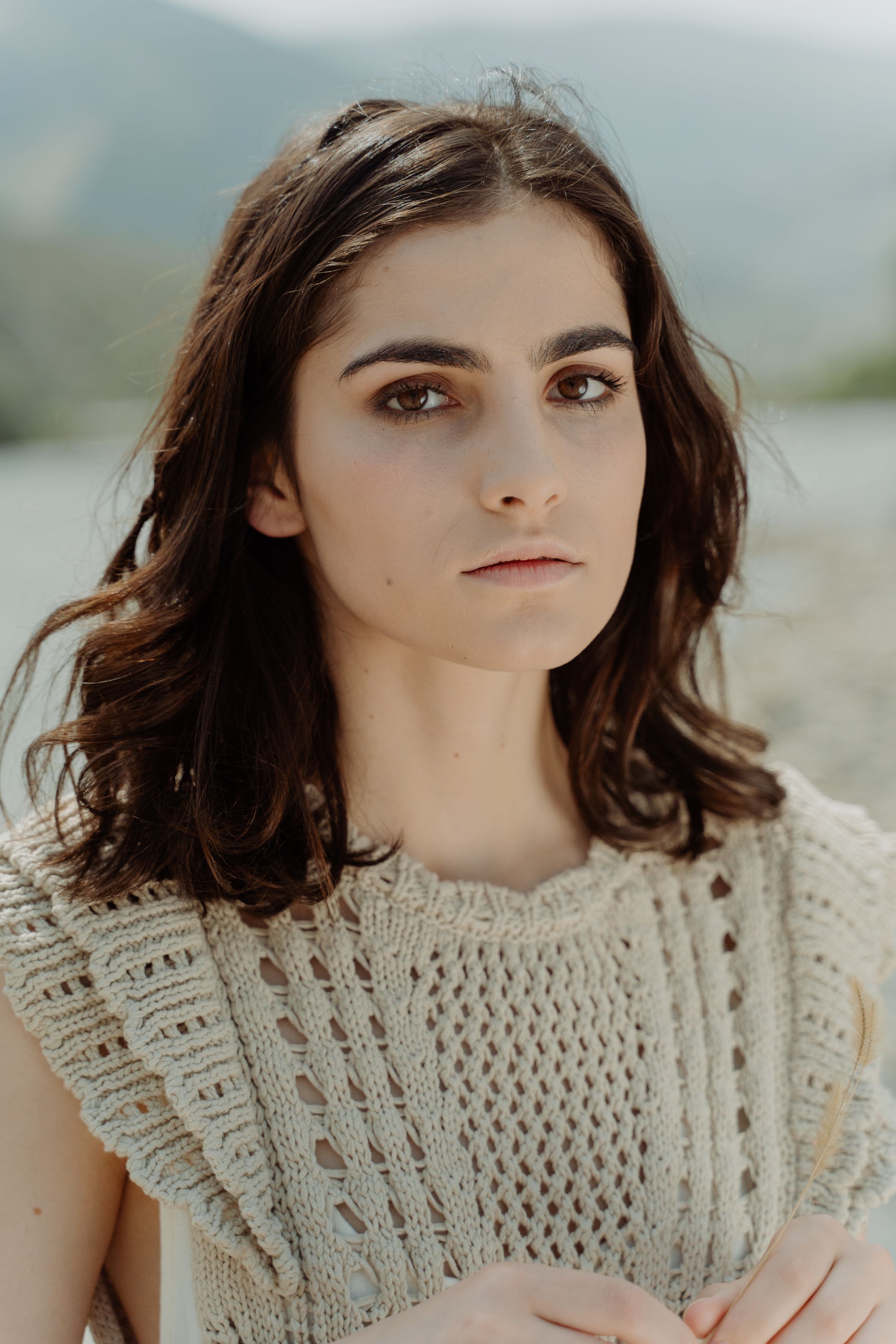 Portrait of a stylish brunette outdoors wearing a knitted top, exuding elegance and natural beauty.