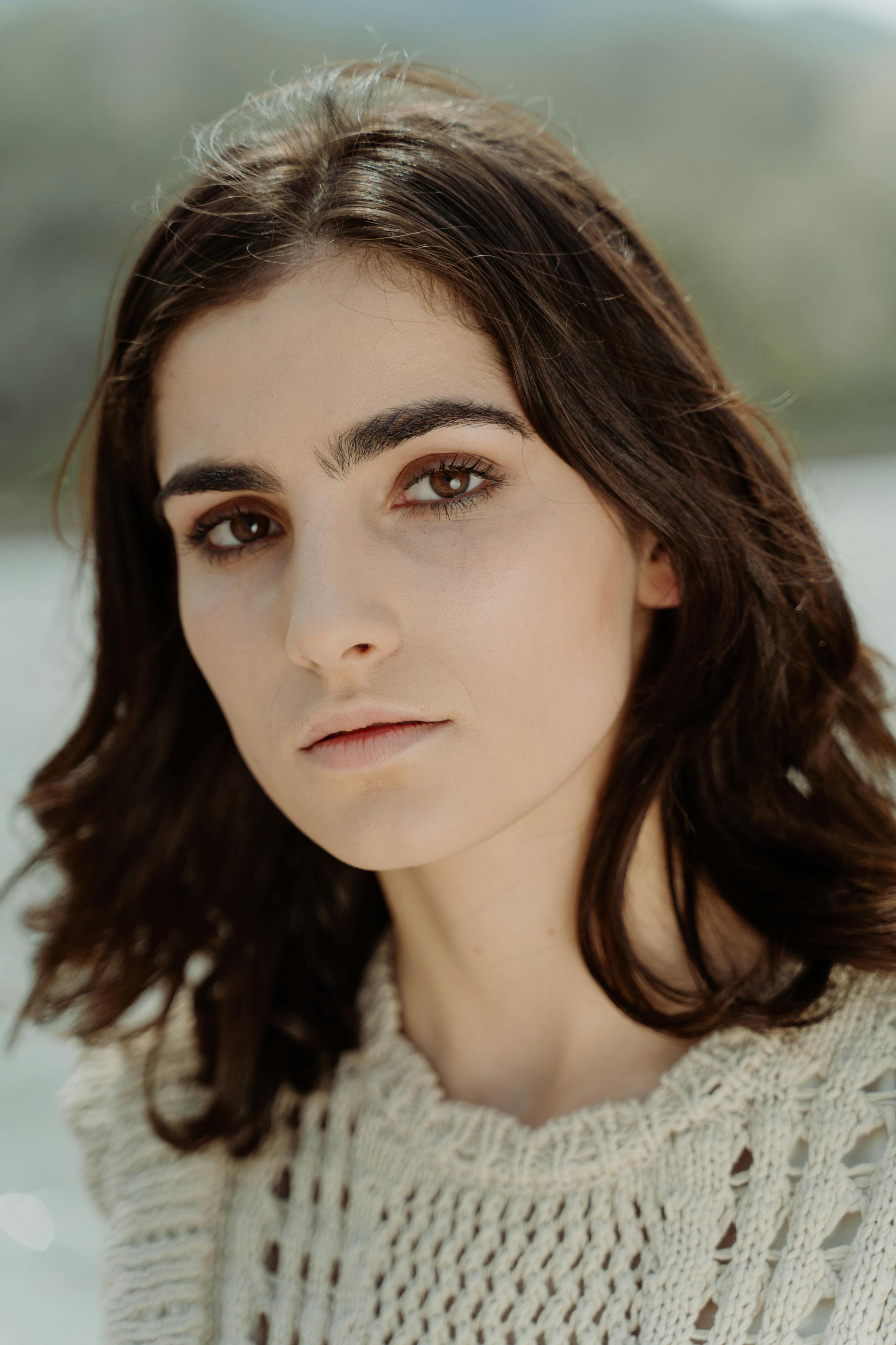 Close-up portrait of a young woman with serious expression, captured outdoors.