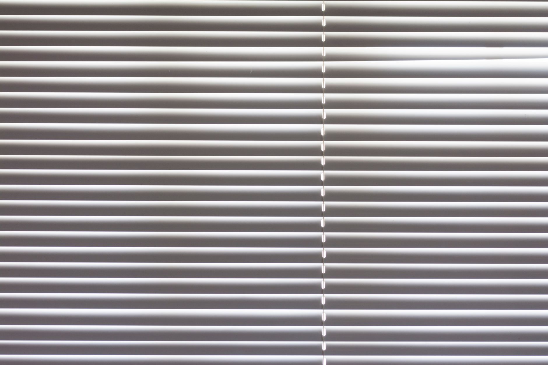Close-up of horizontal window blinds indoors with natural light highlighting texture.