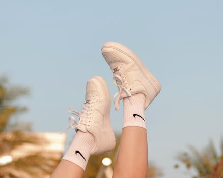 Close-up of white sneakers and socks against a clear blue sky with copy space.