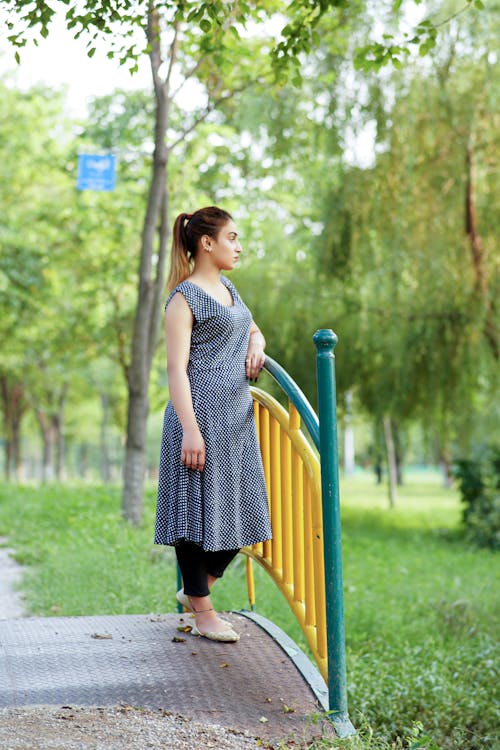 A Woman Leaning on a Metal Fence