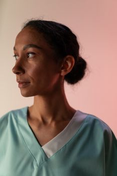 Portrait of a nurse looking away, wearing protective workwear in a studio setting.