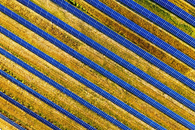 Aerial view of long rows of solar panels across open ground — photo by Tom Fisk on Pexels