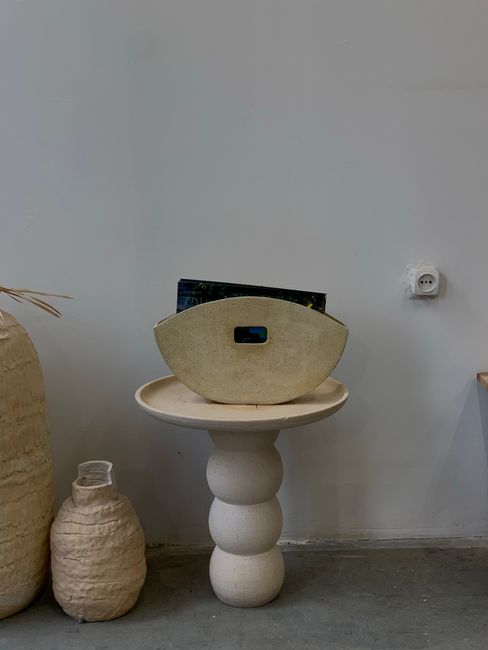 A modern minimalist ceramic vase on a unique pedestal table in a stylish interior setting.