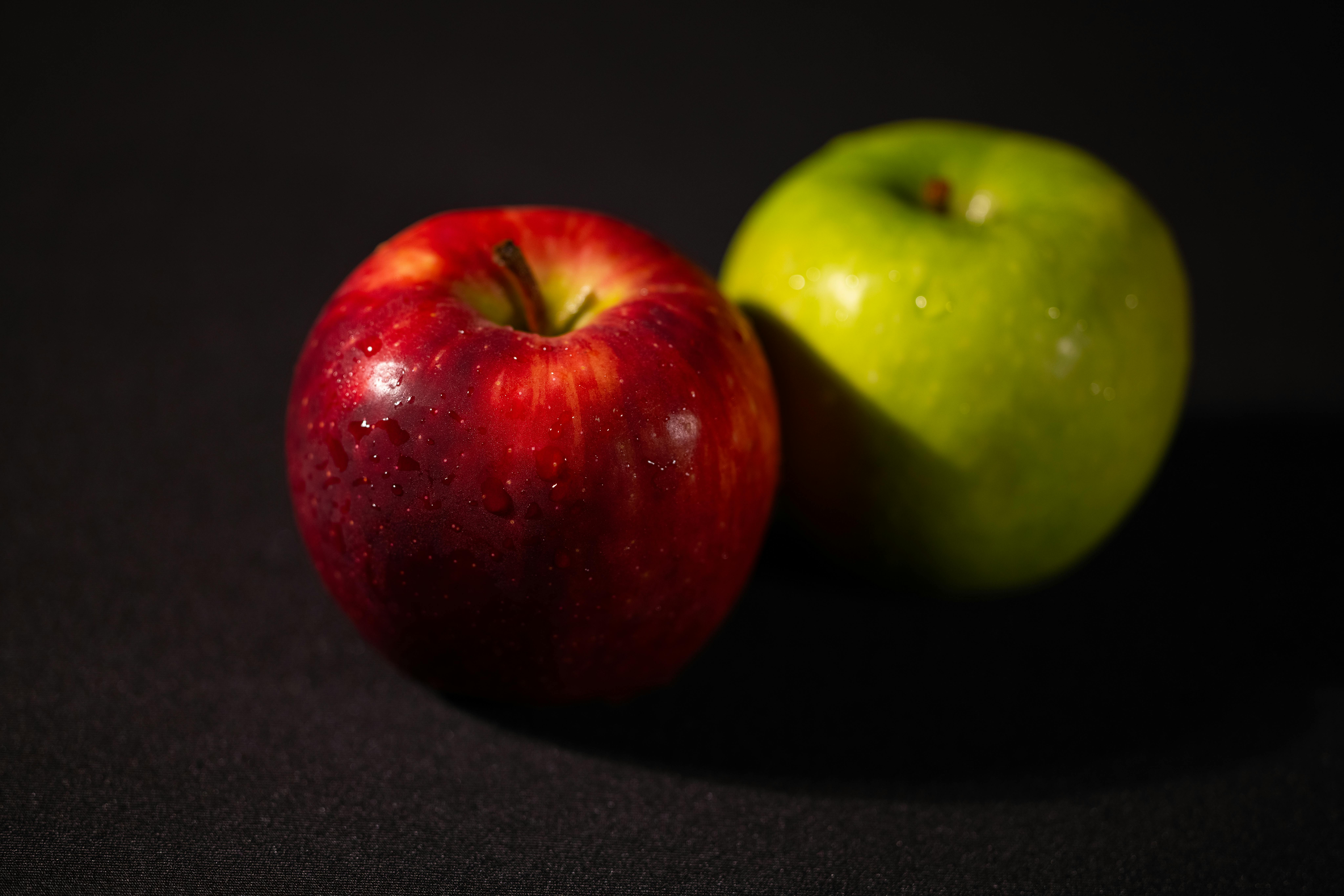Close-up of a red and green apple with water droplets, showcasing freshness and vibrant colors.