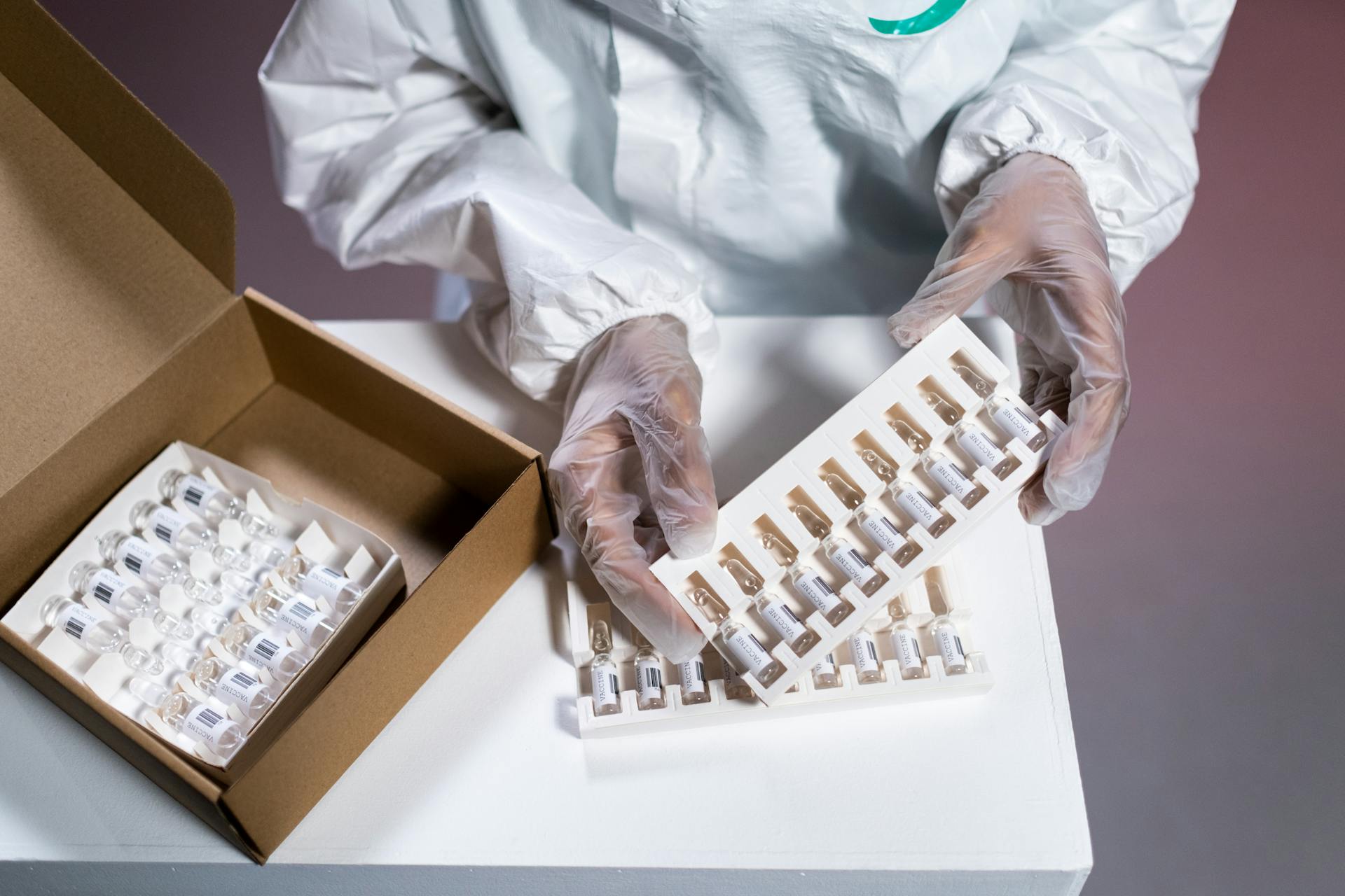 Hands in Plastic Gloves Holding A Box With Vaccines