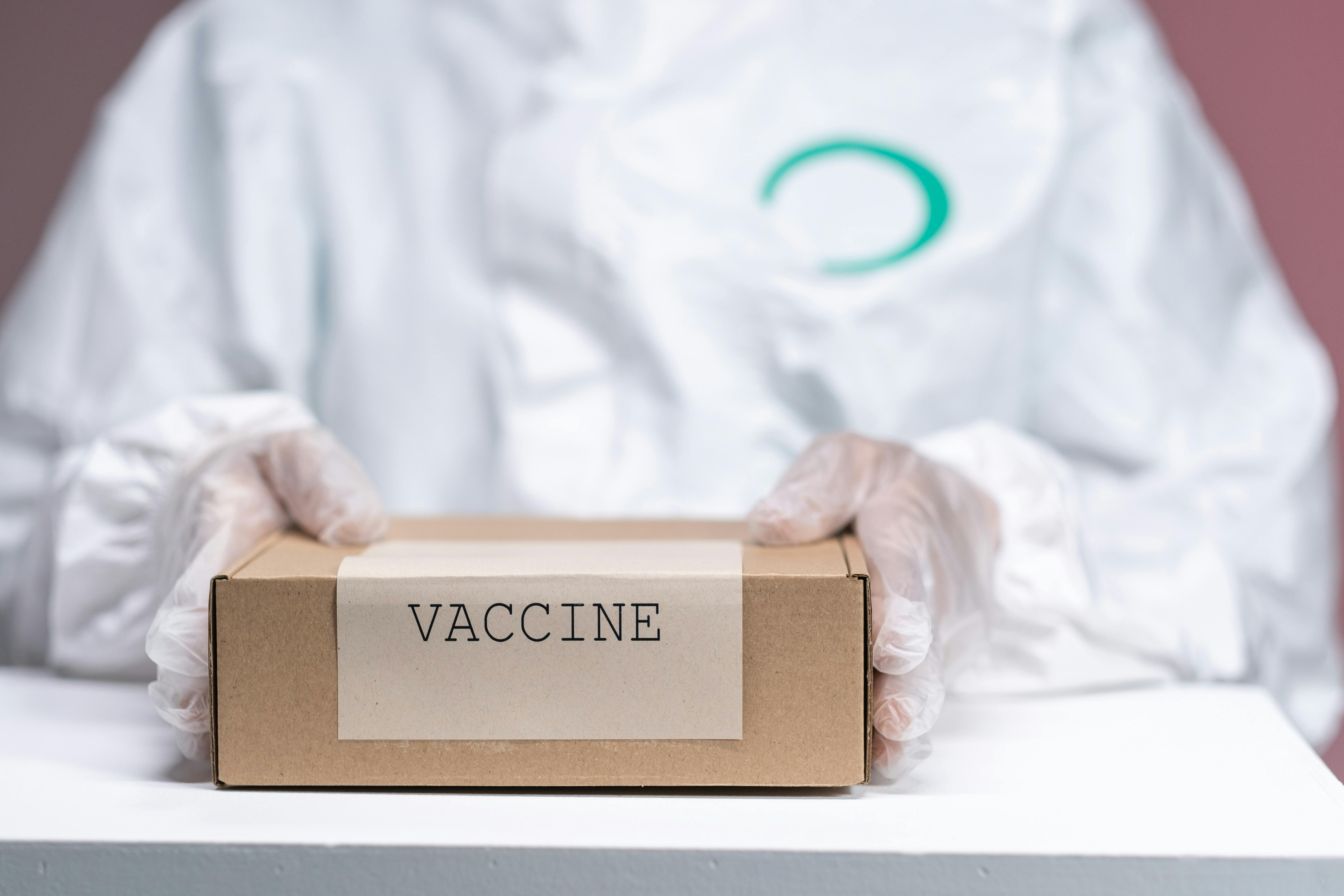 hands in plastic gloves on a box with vaccines