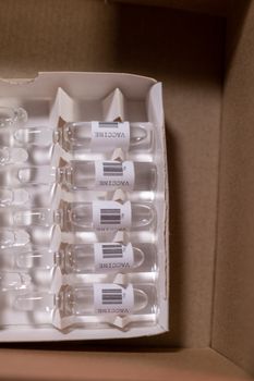 Close-up of vaccine ampoules in a cardboard box, ideal for healthcare and COVID-19 themes.