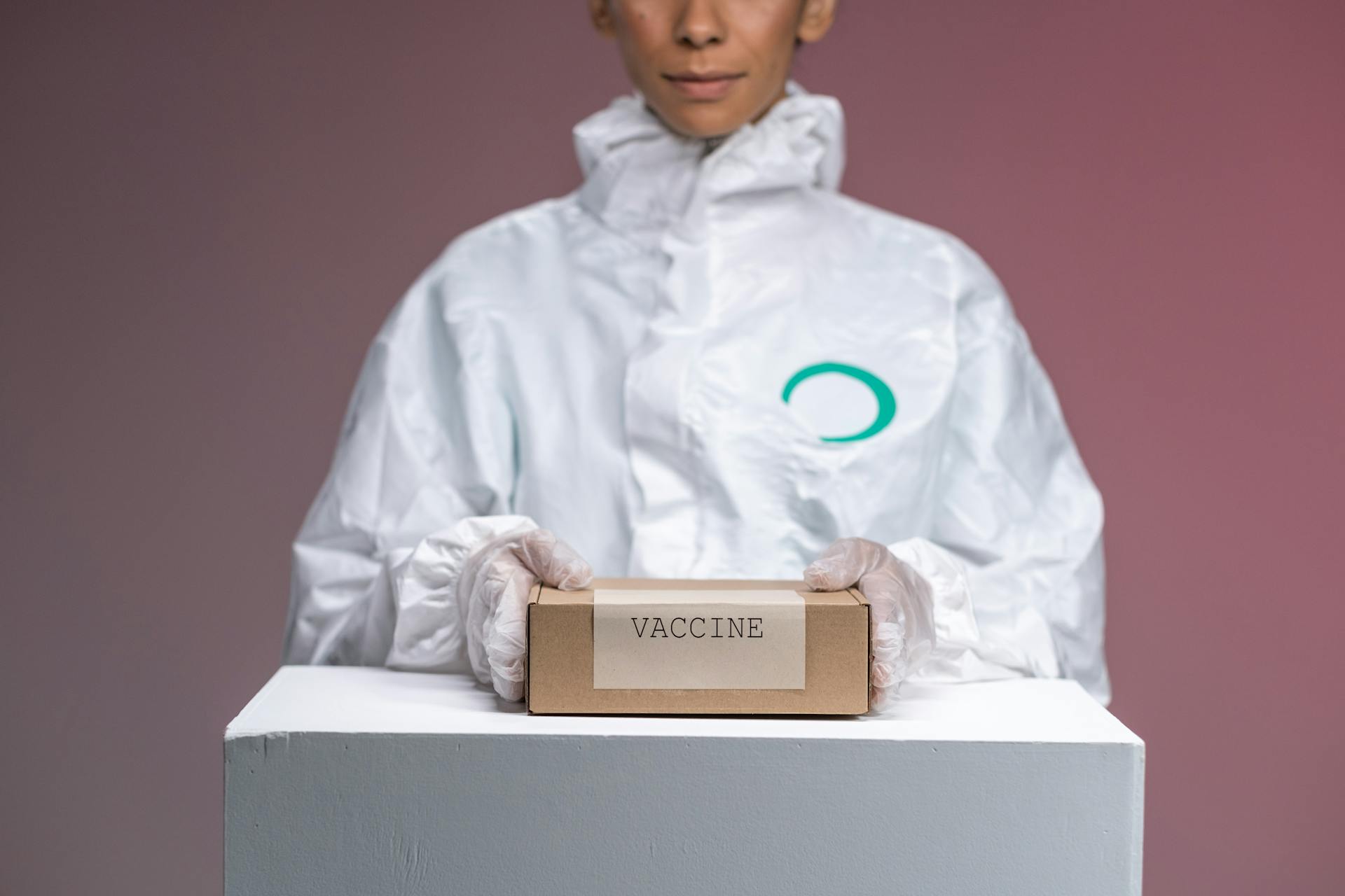 Woman in Protective Uniform Holding Box with Vaccines