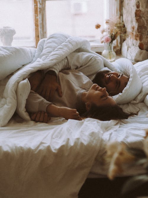 Free Man Smiling in Bed with Woman Stock Photo