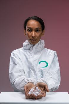 A healthcare worker in a protective suit holds capsules, highlighting safety and medical care themes.