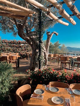 Enjoy dining al fresco on a sunny restaurant patio surrounded by flowers and trees.