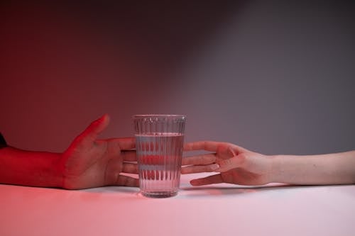 Close up on Human Hands by Glass of Water