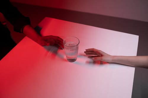 Free Two Peoples Hands Reaching Glass of Water Stock Photo
