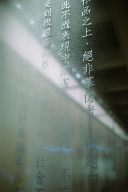 Close-up shot of Chinese script text on a transparent glass surface with light reflections.