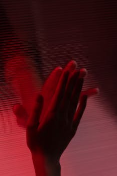 A creative depiction of a hand silhouette illuminated by red light, evoking mystery and intrigue.