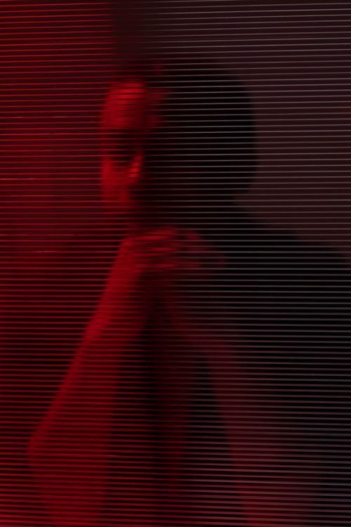 Free A dramatic portrait of an adult man, bathed in red light with striking shadow effects. Stock Photo