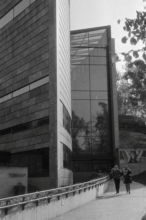 Black and White Photo of People Walking by a Building