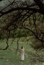 Woman in White Dress Standing on Green Grass Field Surrounded by Trees