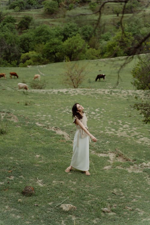 Photo of a Woman with a White Skirt Standing on Green Grass