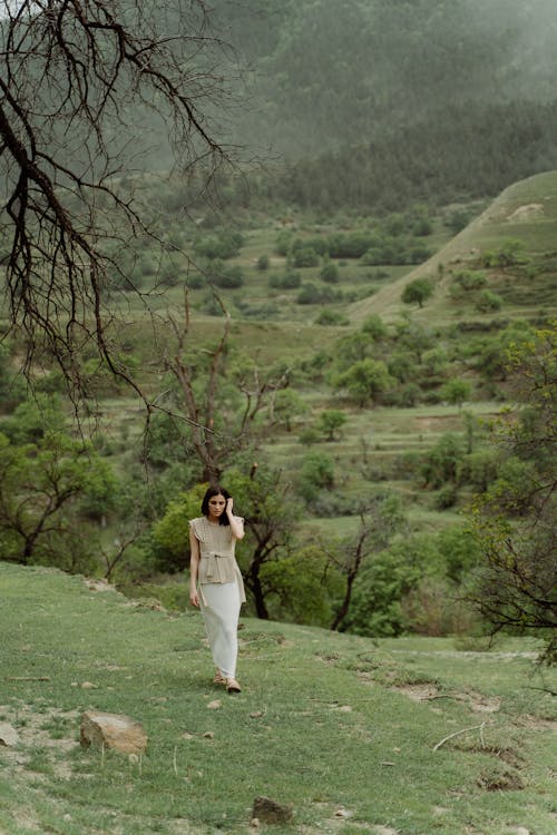 Woman in a White Skirt Walking on Green Grass