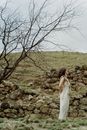 Woman in White Dress Standing on Rocky Ground