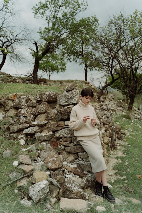 Woman in a Beige Sweater Leaning on Rocks