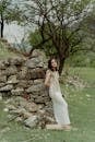 Woman in White Sleeveless Dress Standing Beside Brown Tree