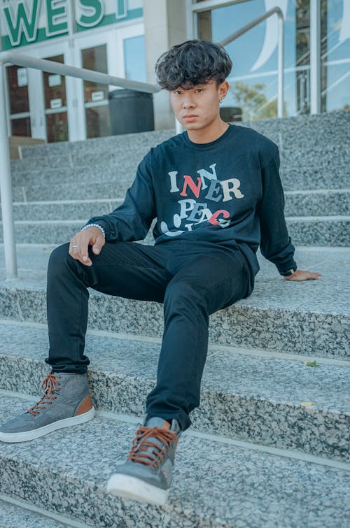 A Boy in Black Long Sleeve Shirt Sitting on Concrete Stairs