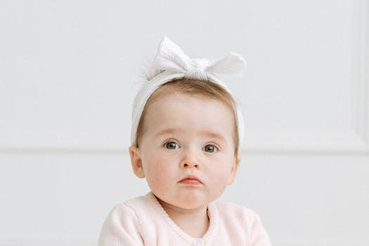 Charming studio portrait of a cute baby with a white bow headband, exuding innocence and sweetness.