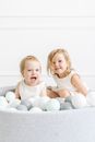 Two Children Playing in a Pool with Balls
