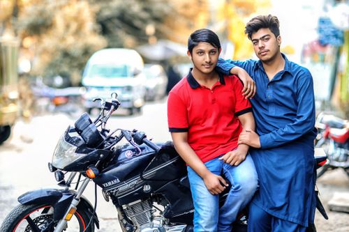 Free Two young men posing with a motorcycle on a sunny day in an urban setting. Stock Photo
