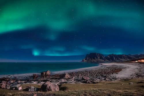 Free Aurora Borealis Sky Over the Sea Near Rocky Mountains Stock Photo