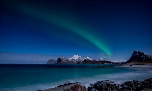 Free Captivating view of the Northern Lights illuminating snowy mountains in Nordland, Norway. Stock Photo